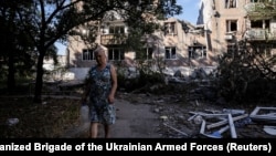 A woman walks near heavily damaged residential buildings in the frontline town of Toretsk in Ukraine's Donetsk region on June 13. 