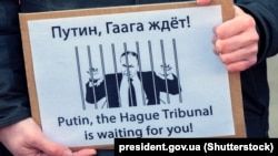 A protester holds up a poster saying "Putin, the Hague Tribunal is waiting for you!" in Amsterdam in March 2022.