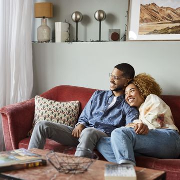 smiling couple looking away while sitting on sofa