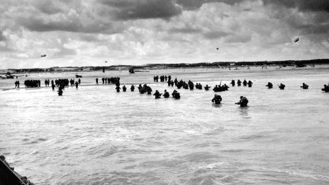 Black and white photograph of troops wading onto the Normandy beaches