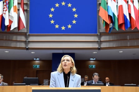 blanchett speaks at desk under EU flag