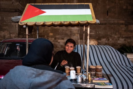 A female vendor serves coffee from a stall adorned with the Palestinian flag in solidarity amid the ongoing conflict in the Gaza Strip, outside the old city walls of Cairo in the district of Gamaliya on Friday.