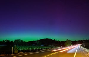A purple, blue and green sky above a highway at night