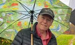 Bruce Joel Rubin holding an umbrella with pictures of birds and grassland on it.