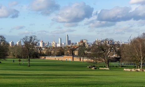 A view over Brockwell Park on a sunny day, with grass, trees and the London skyline in the distance.