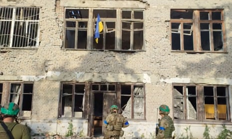 Soldiers waving a Ukrainian flag out of window of bombed-out flat