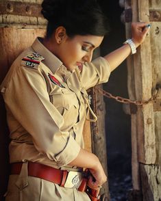 a woman in uniform is leaning against a wall with her hand on the door handle