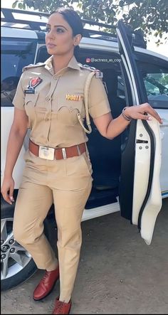 a woman in uniform standing next to a car with her hand on the door handle