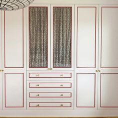 an empty room with white cabinets and red trimmings on the doors, window coverings and curtains