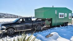 a truck with a trailer attached to it parked in the snow