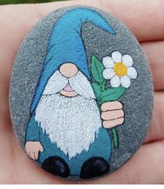 a hand painted rock with a gnome holding a flower