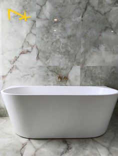 a white bathtub sitting on top of a marble floor next to a wall with yellow numbers