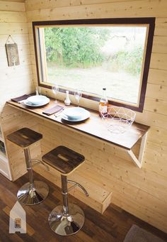 two stools sit in front of a window on the inside of a tiny cabin