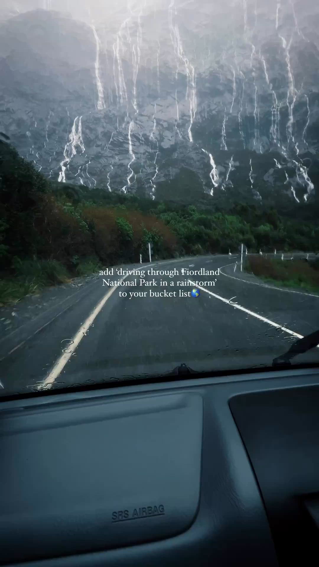 This may contain: a car driving down a road with mountains in the back ground and lightning coming from behind it