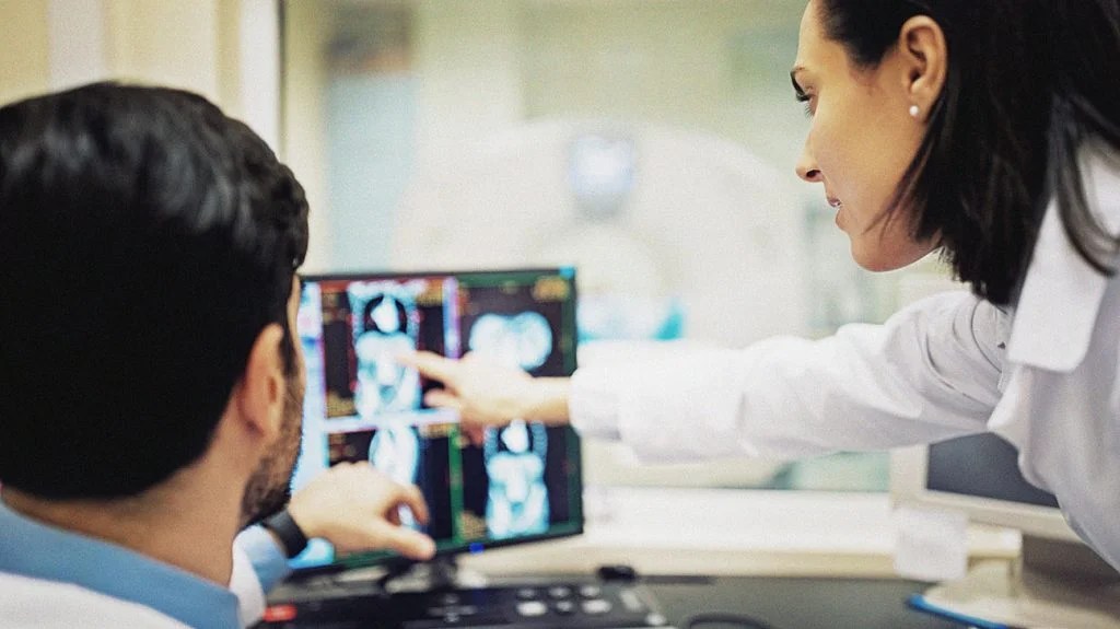 a doctor and patient look at scans on a screen while discussing types of radiation therapy