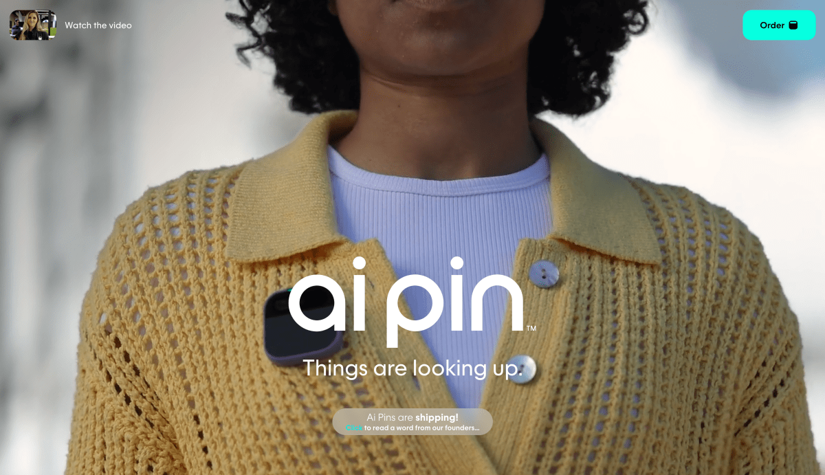 Frontspiece of the AI Pin website. Tight closeup of a human being wearing the product, a pin affixed to her cable knit sweater.