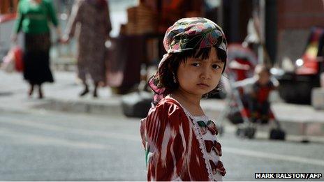 A young Uighur girl waits near the main bazaar in the Muslim quarter of Urumqi, Xinjiang Province on June 29, 2013