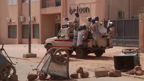 Reuters Riot policemen driving towards protesters at a makeshift checkpoint in Niamey, Niger