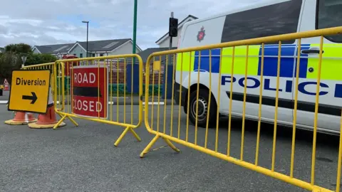 BBC Road closed sign, police van and yellow fencing