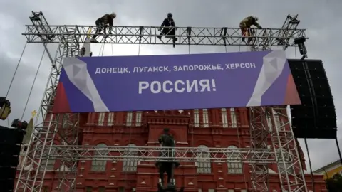 NATALIA KOLESNIKOVA/AFP Workers fix a banner reading "Donetsk, Lugansk, Zaporizhzhia, Kherson - Russia!" on top of a construction installed in front of the State Historical Museum outside Red Square in central Moscow on September 29, 2022