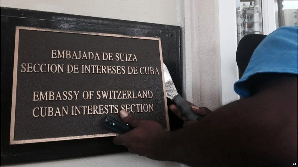 A worker removes the Cuban Interests Section sign in Washington, just days prior to the building being accredited as the Cuban Embassy (15/07/2015)
