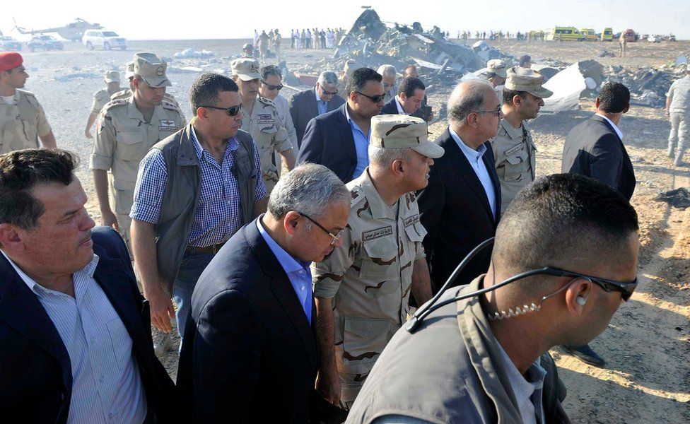 In this image released by the Prime Minister"s office, Sherif Ismail, third right, along with milirary and government officials, tour the site where a passenger plane crashed in Hassana Egypt, Friday, Oct. 31, 2015.