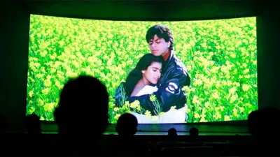 Bollywood actors Shah Rukh Khan and Kajol are seen on the screen during the screening of "Dilwale Dulhania Le Jayenge" inside Maratha Mandir theatre in Mumbai