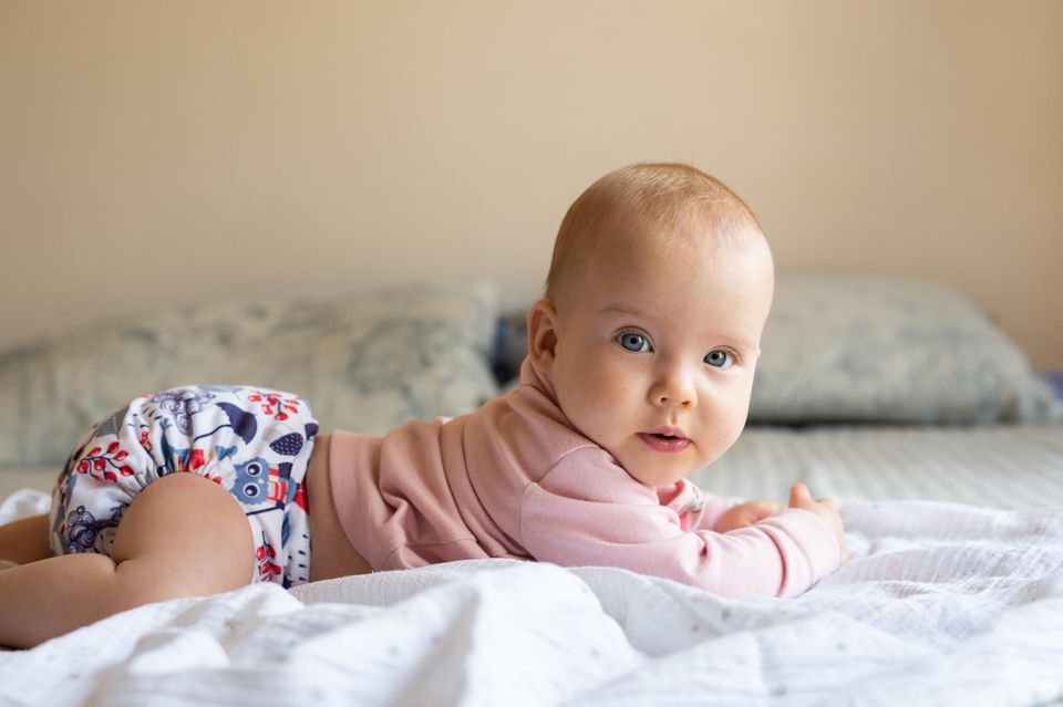 Stoffwindel im Test: Zufriedenes Baby liegt in Stoffwindel auf Bett