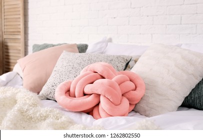 Different pillows on bed in room. Idea for interior decor with living coral color Arkivfotografi