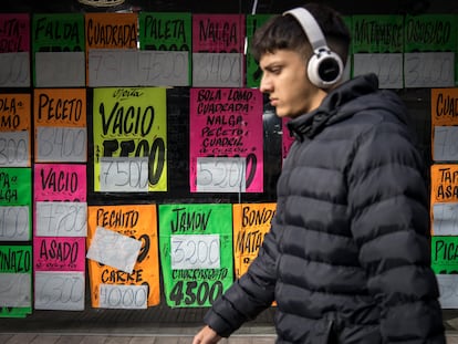 Un joven pasa frente a una carnicería con precios a la vista, en Buenos Argentina, Argentina, en 2024.
