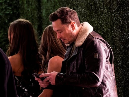 Elon Musk uses his phone before the premiere of ''Lola'' held at the Regency Bruin Theatre in Los Angeles, California, U.S.,  February 3, 2024.