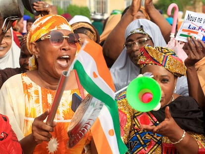 Una persona sostiene un papel en el que se lee "Ya no queremos a Francia", mientras varias mujeres se manifiestan en apoyo a los golpistas frente al cuartel general del Ejército francés, en Niamey, Níger, el 30 de agosto.