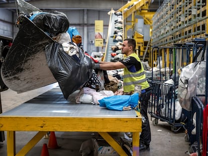 Un operario descarga ropa en la planta de tratamiento textil de Koopera Mediterránea en Ribarroja de Turia (Valencia).
