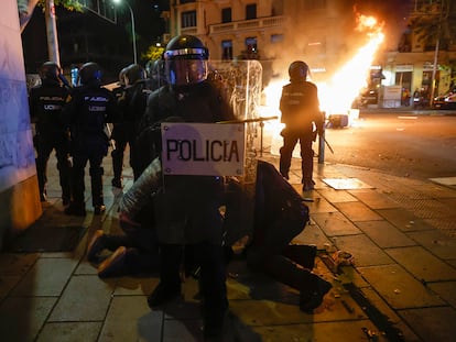 La policía detenía a una persona en Madrid al final de la protesta del jueves, mientras al fondo ardía el mobiliario urbano.