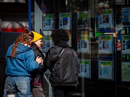 Unas jóvenes observan la oferta de pisos en alquiler de una oficina inmobiliaria de Madrid.