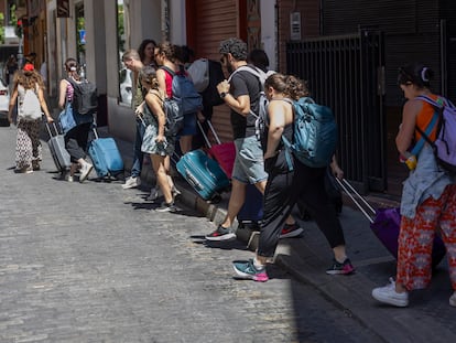 Un fila de turistas con maleta en Sevilla.