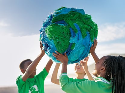 Un grupo de jóvenes activistas por el clima sujeta un globo terráqueo junto a la orilla del mar.