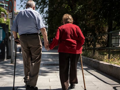 Un hombre y una mujer mayores caminando cogidos de la mano por la calle Caramuel, en el barrio de Puerta del Angel, Madrid. 
Foto: Olmo Calvo