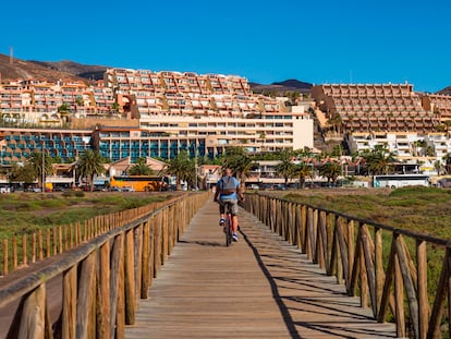 Un hombre monta en bici junto a varios edificios de apartamentos en Fuerteventura.