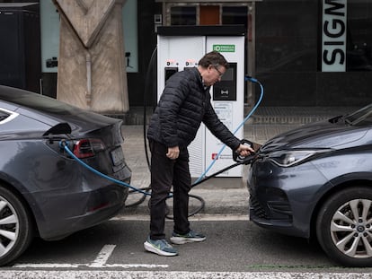 Un hombre carga su coche eléctrico en una calle da Barcelona.