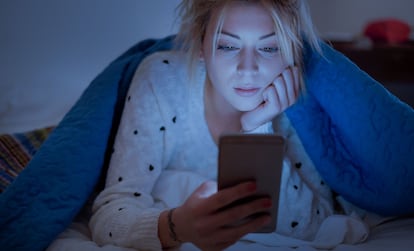 Una joven consulta su móvil antes de dormir.