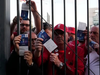 Liverpool fans show tickets and wait in front of the Stade de France prior the Champions League final soccer match between Liverpool and Real Madrid, in Saint Denis near Paris, Saturday, May 28, 2022. Police have deployed tear gas on supporters waiting in long lines to get into the Stade de France for the Champions League final between Liverpool and Real Madrid that was delayed by 37 minutes while security struggled to cope with the vast crowd and fans climbing over fences. (AP Photo/Christophe Ena)