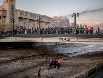 Un joven es atendido por personal de rescate en el lecho del río Mapocho, luego que un carabinero antimotines lo lanzara desde el puente Pío Nono, en octubre de 2020.