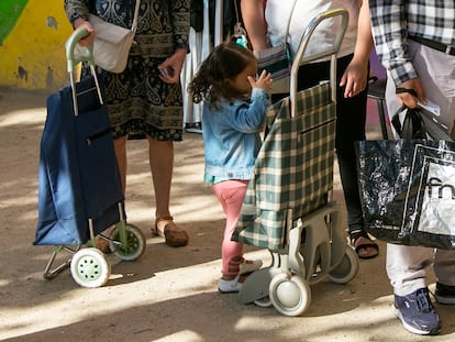 Una menor, junto a su familia, en una cola para el reparto de alimentos en Madrid.