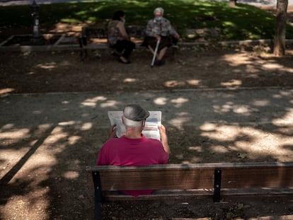Una persona mayor lee un periódico en un parque de Madrid.