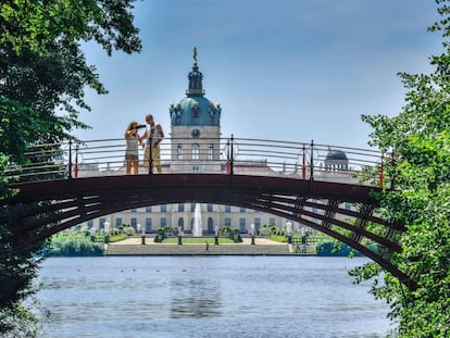 Una pareja hace una foto del palacio de Charlottenburg desde un puente sobre el río Spree, en Berlín.