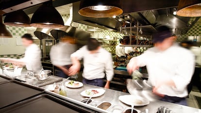 Varios cocineros trabajan en el interior de una cocina profesional.