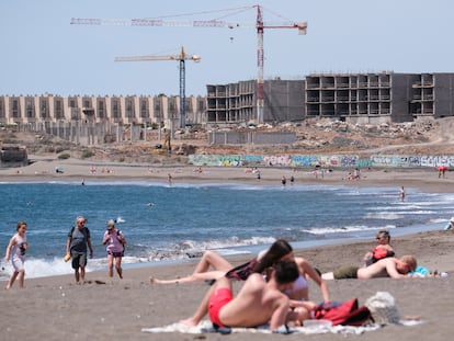 Turistas disfrutan del mar y el sol frente a las obras de construcción de un hotel en la playa de La Tejita, en el sur de Tenerife.