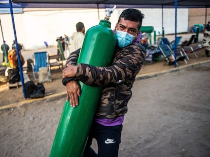Un hombre carga con un tanque de oxígeno vacío mientras llega a la cola para rellenarlo en Villa El Salvador, en las afueras del sur de Lima.