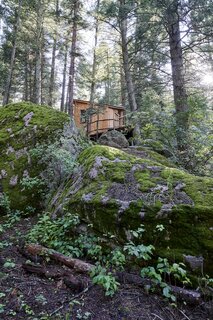 Moss-covered boulders at the base of Colorado Camelot tree house helped to inspire the design for the compact structure.
